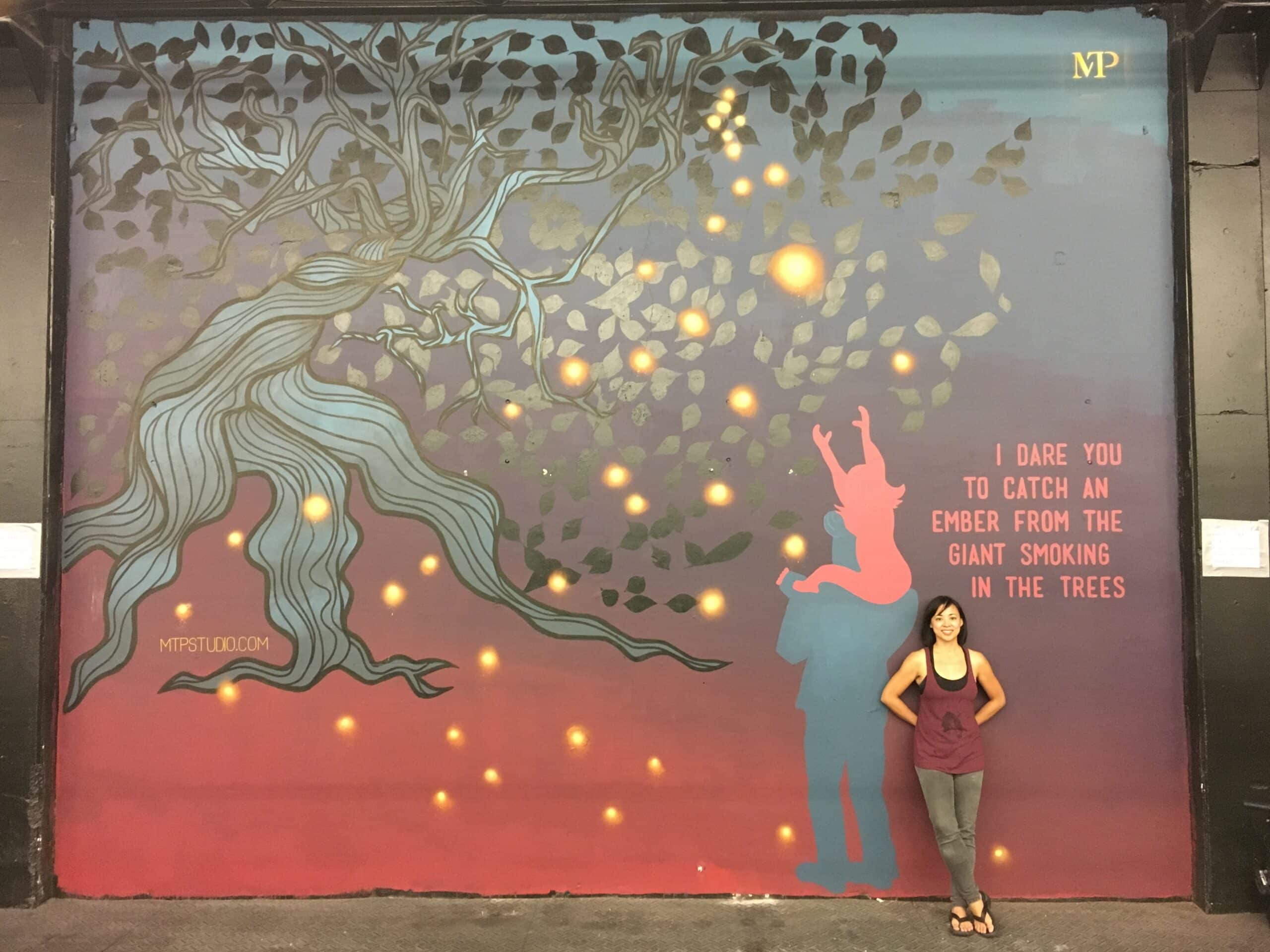Fireflies Mural with Monette standing in front of it